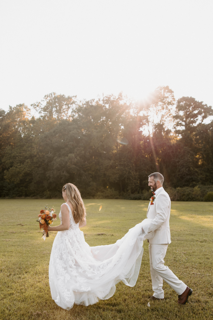 Bride holding bouquet and groom holding the brides dress.