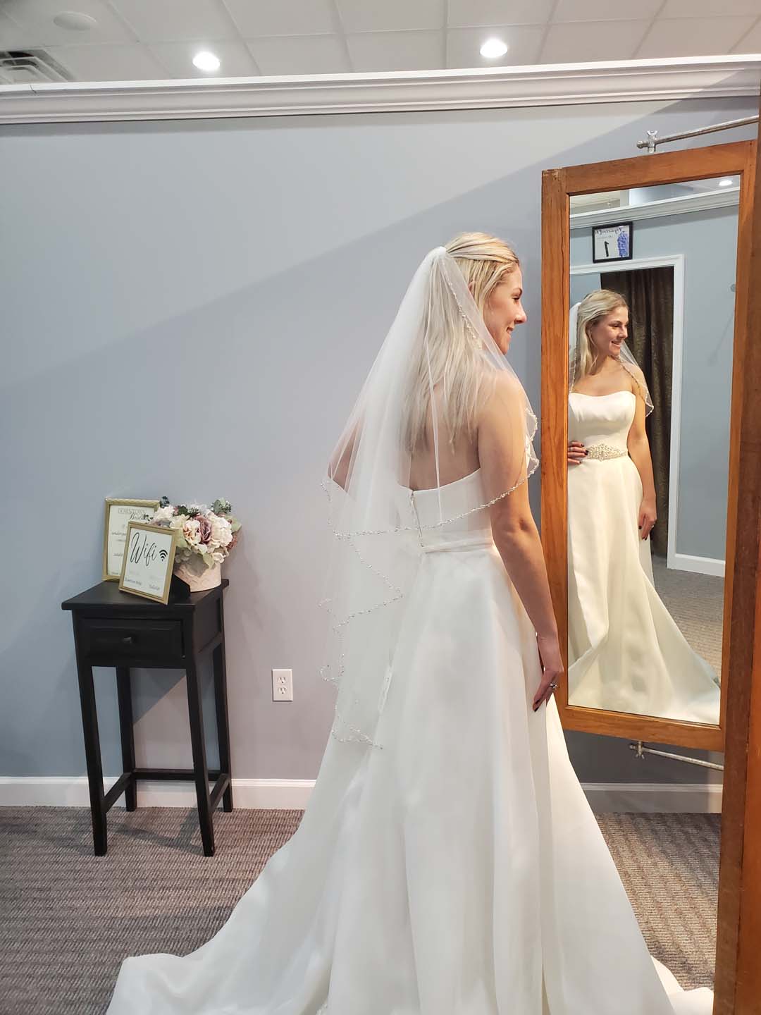 Bride trying on white dress in bridal store.