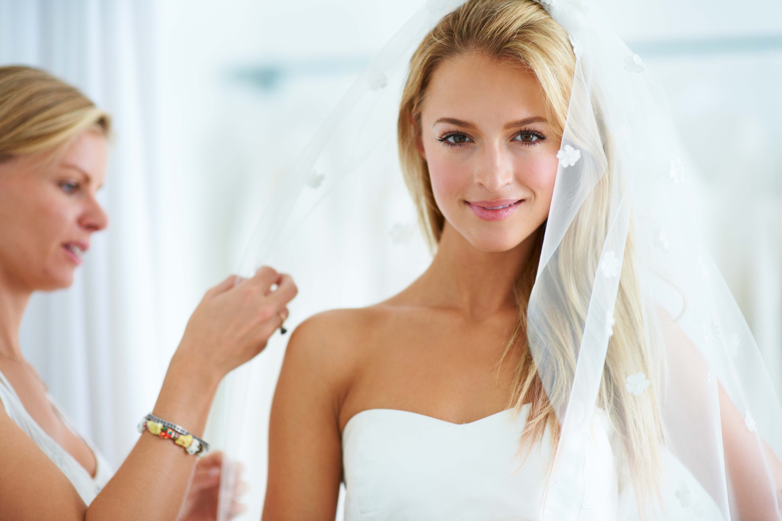 A bride in white wedding dress and veil getting ready.
