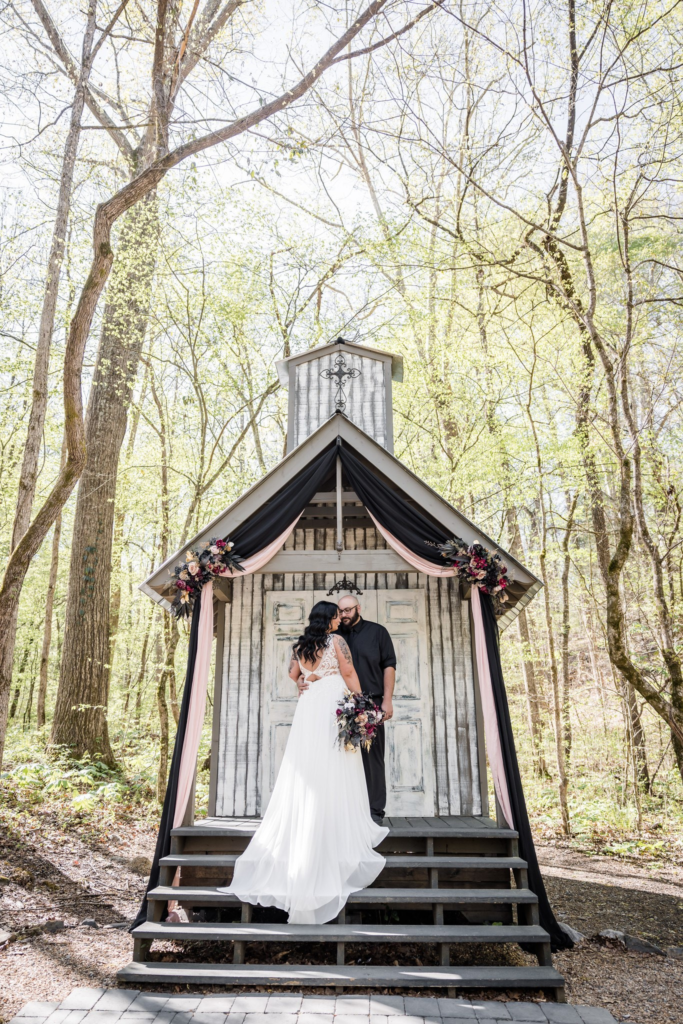 Bride and groom posing in front of a make shift chapel.